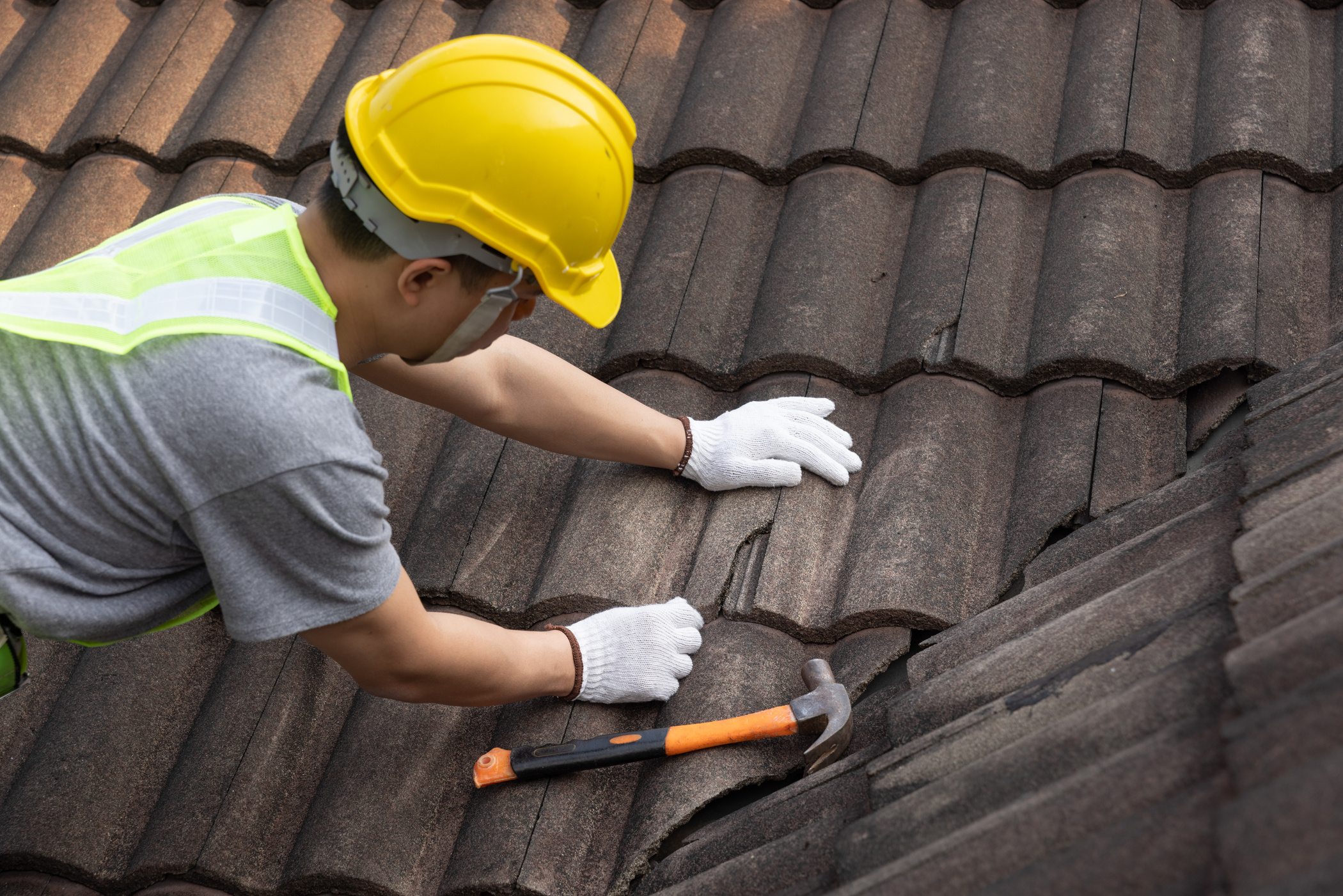 Worker man replace tile of the old roof. Repair roof concept.